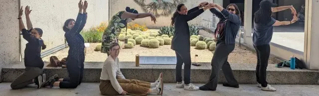 Seven people pose to spell "CAREER" in front of a cactus garden.