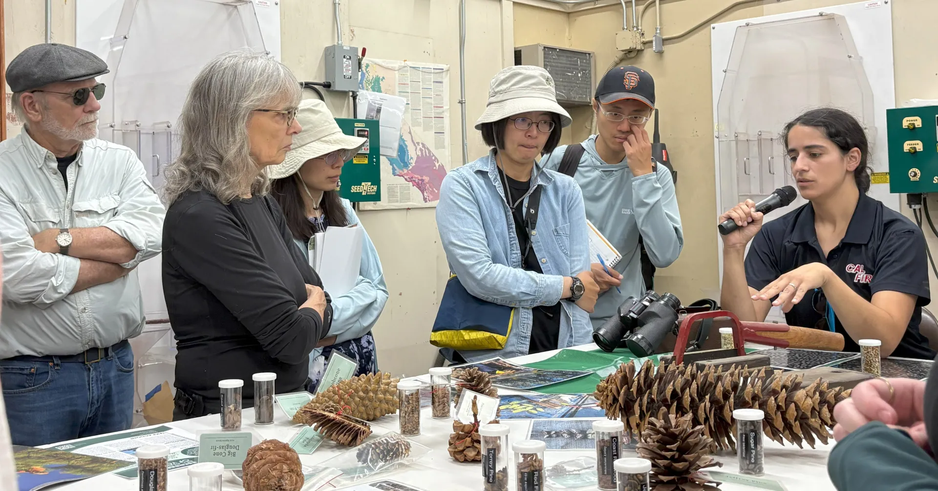 A group of people standing inside listening to a presenter.
