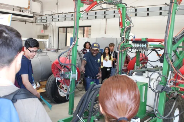 Dr. Peter Larbi interacting with student volunteers to demonstrating spray coverage during workshop.