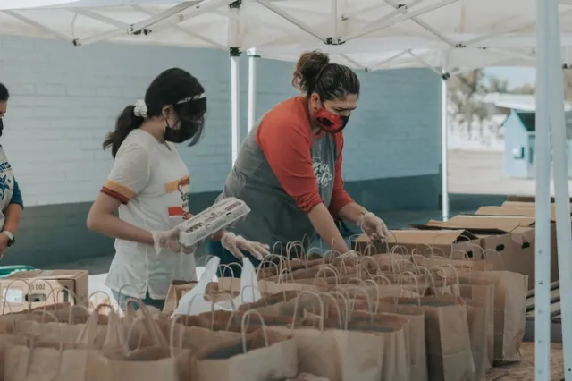 Two people putting food in paper bags