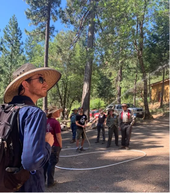 A man is holding a hose in the distance, pointing it upward with water spouting out.
