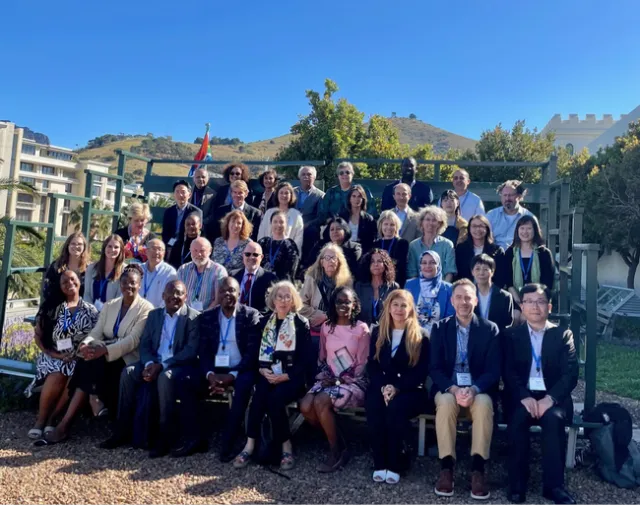 Forty one people sit in bleachers outdoors for group photo.