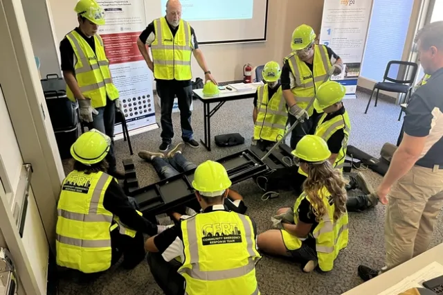 Participants in emergency preparedness training practice using a pry bar to move an object off of a person
