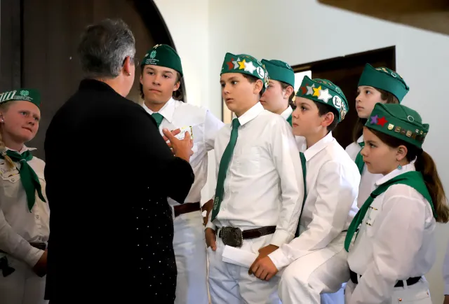 A woman talks to a group of young people in 4-H uniforms.