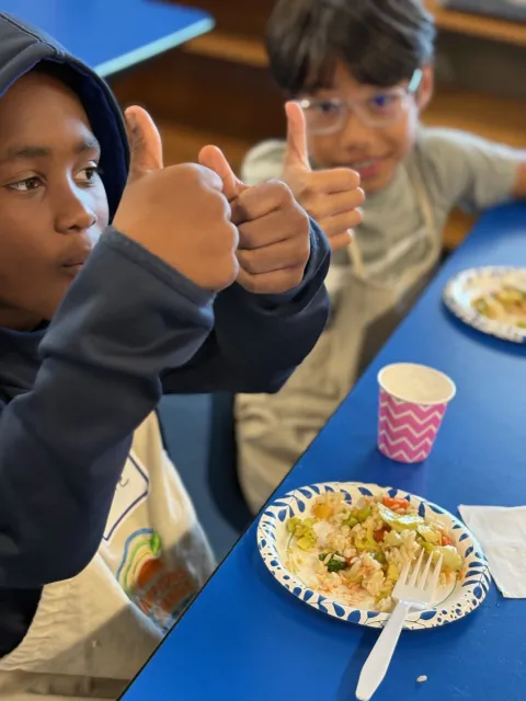 Two boys giving a thumbs-up to a taste of stir-fry from their EFNEP class.
