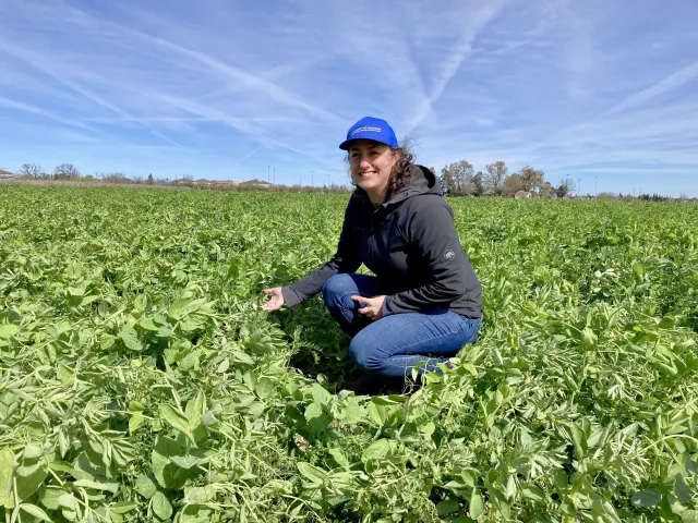 Sarah Light crouches in a field and smiles