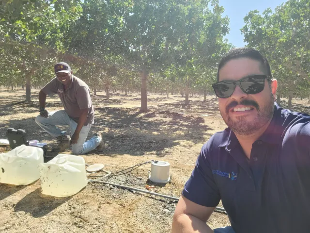 Leonel Jimenez with Tobias Oker crouched in an orchard in the background
