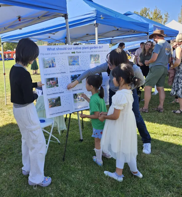 Children gather around a poster in a public park