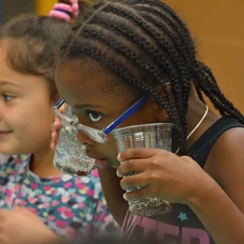 Young scientists using the sense of hearing to listen to soda bubbles during a Kitchen Science YES Project lesson.