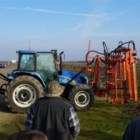 Tractor in a field surround by several farmers.