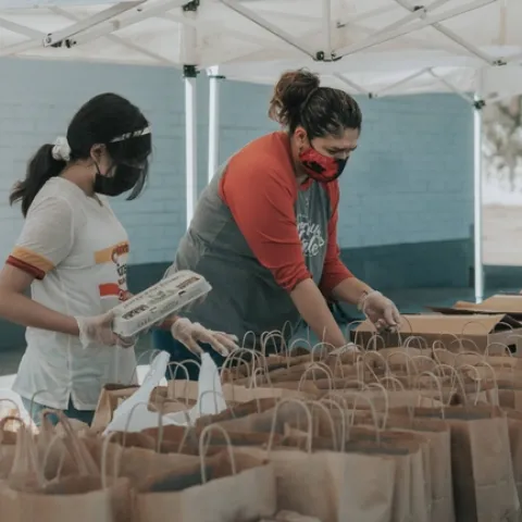 Two people putting food in paper bags