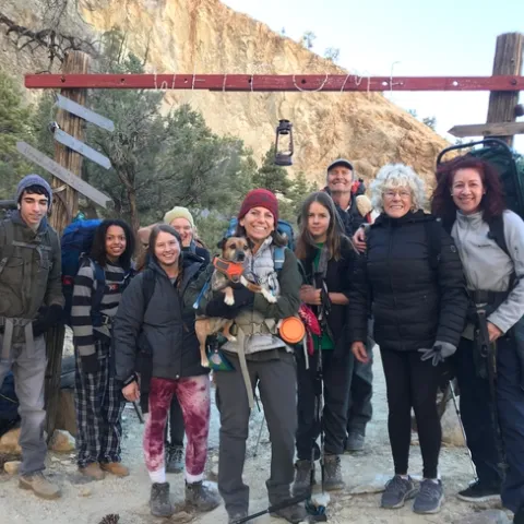 A group people posing in front of a "Welcome" sign while on a backpacking trip.