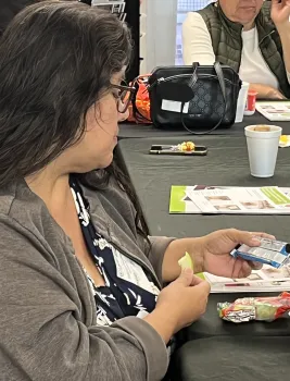 Woman eating an apple slice while reading the nutrition facts for a snack bar.