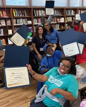Adult participants showing their graduation certificates.
