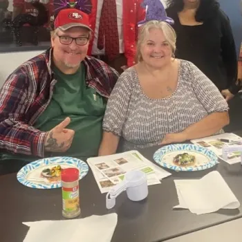 Man and woman sitting at a table with EFNEP class handouts and food.