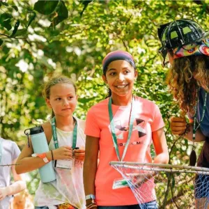 An adult holding a net talks to a group of children outdoors