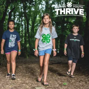 Text in right corner says "helping youth thrive" 3 children walk towards the camera. One is wearing a 4-H T-shirt