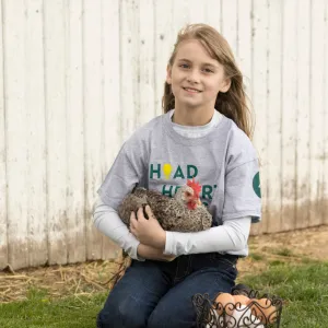 Youth kneels holding a chicken in her arms